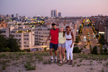 Obraz premium Diverse friends walking and smiling enjoying city views at dusk
