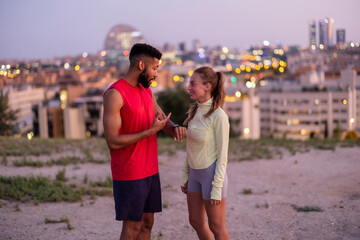 Fototapeta premium Couple discussing fitness data on smartwatch during evening workout