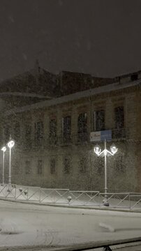 Heavy snow falls on a silent residential street in &Aacute;vila at night, covering pavements, parked cars and trees, while soft street lighting adds a peaceful, wintry atmosphere to the urban landscape.