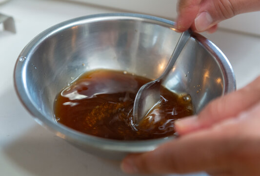 ボウルに入れた調味料をスプーンで混ぜる風景　ソースやタレを手作りする家庭料理のシーン