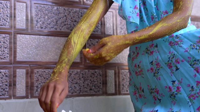A woman applying homemade ubtan skincare mask on her arm and hands. Close up of Lady using natural cosmetic on body. Ayurvedic beauty treatment for clean skin. Ubtan paste massage at home.