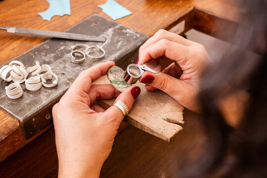 Craftsman Checks Variscite Stone With Magnifying glass  in a Workshop and Focuses on Intricate Details While Working