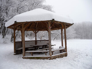 Tische und B&auml;nke in einem Holzpavillon, rundherum nur Schnee.
