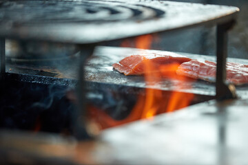 Beef steak grilling over open fire on barbecue grill with flames and smoke. Ideal for: food advertising, barbecue marketing, restaurant promotion, outdoor cooking, premium meat concepts.