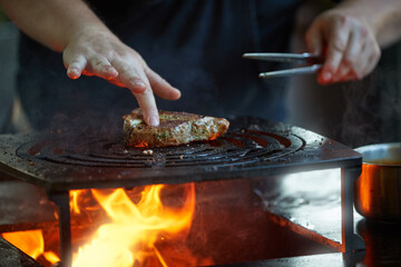 Grilling meat on open fire pit with dynamic flames for outdoor gourmet barbecue and catering services