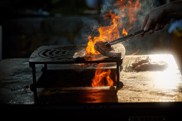 Grilling meat on open fire pit with dynamic flames for outdoor gourmet barbecue and catering services