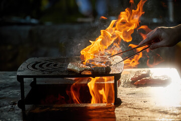 Grilling meat on open fire pit with dynamic flames for outdoor gourmet barbecue and catering services