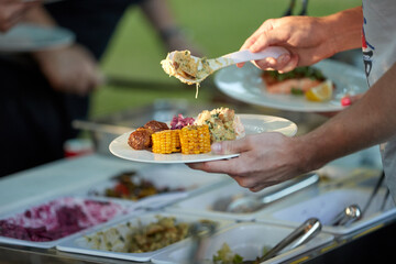 Catering staff serving prepared meals from a buffet line during a professional event, ideal for: corporate catering, hospitality services, food service operations, business events.