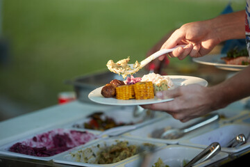 Catering staff serving prepared meals from a buffet line during a professional event, ideal for: corporate catering, hospitality services, food service operations, business events.