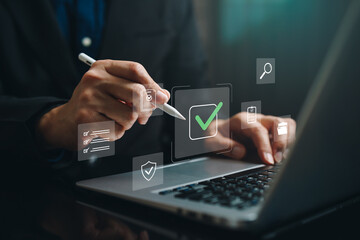 Hand using stylus on laptop with digital checkmark and checklist icon, representing approval...