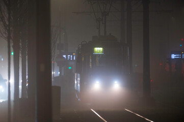 Ż&oacute;łty tramwaj we mgle, jadący ulicą Marszałkowska w Warszawie.