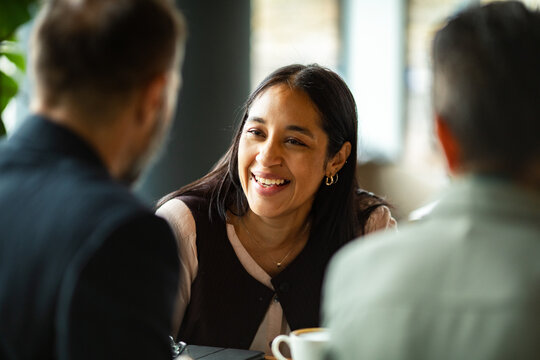 Smiling woman chatting with colleagues at cafe table