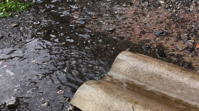 Water flows down a gutter onto the asphalt