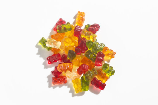 Colorful gummy bears pile on a white background, representing sweet treats and childhood