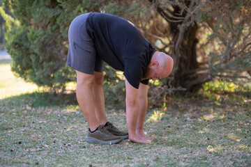 Outdoor Stretching Exercise in Green Park. Healthy Lifestyle Concept with Man Stretching Outside. Man Stretching in the Park. Man Warming Up with Stretching Exercises Outdoors.