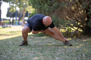 Outdoor Stretching Exercise in Green Park. Healthy Lifestyle Concept with Man Stretching Outside. Man Stretching in the Park. Man Warming Up with Stretching Exercises Outdoors.