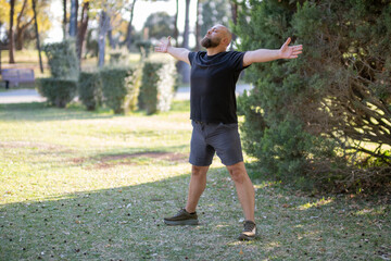 Outdoor Stretching Exercise in Green Park. Healthy Lifestyle Concept with Man Stretching Outside. Man Stretching in the Park. Man Warming Up with Stretching Exercises Outdoors.