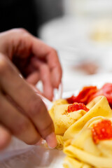 Hand adding red caviar to delicate crepes for a sophisticated appetizer