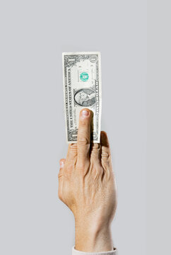 Hand holding dollar bill on gray background