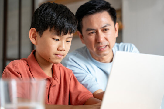 Father and son bonding over laptop at home