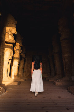 Woman exploring ancient Egyptian temple in sunlit corridor