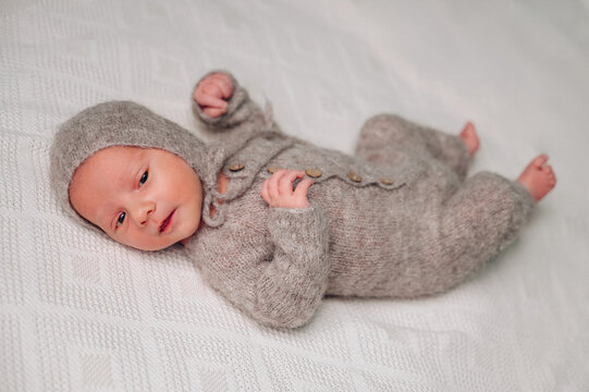 Cozy newborn in knitted outfit on soft bed