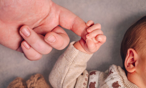 Newborn holding a parent's finger in a gentle embrace
