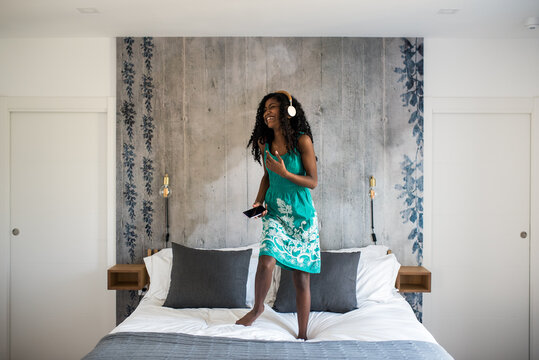 Girl joyfully dancing with headphones on bed