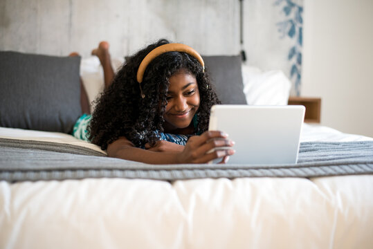Girl enjoying tablet while relaxing in bedroom
