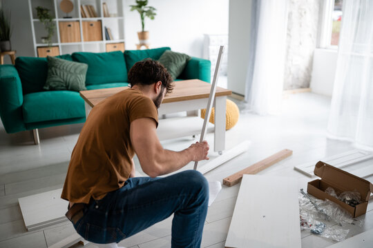 Man assembling ikea furniture in new home living room