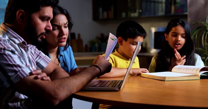 Indian young couple managing finance while kids reads book at modern home as parents work on laptop and financial documents while son and daughter study together showing family money planning