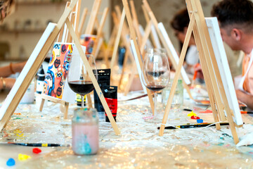 Friends enjoying art and wine workshop painting canvases