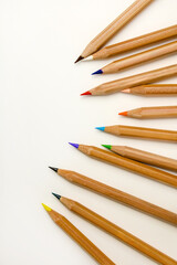 Fototapeta premium Minimalist flat lay of sharpened wooden colored pencils arranged diagonally on a white background with copy space, symbolising creativity, art, design, education, and choice.