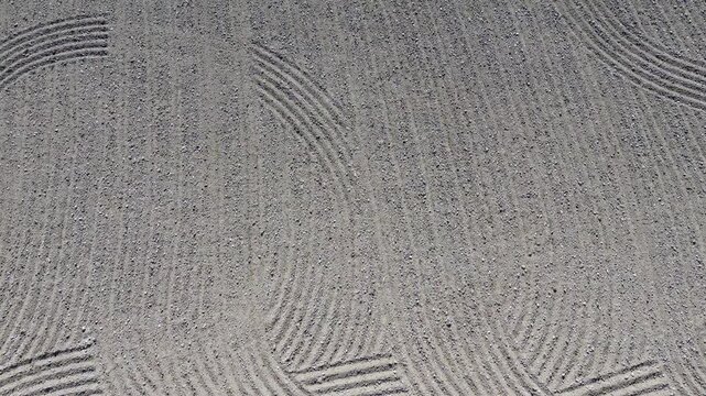 Abstract grey raked sand texture with curved patterns