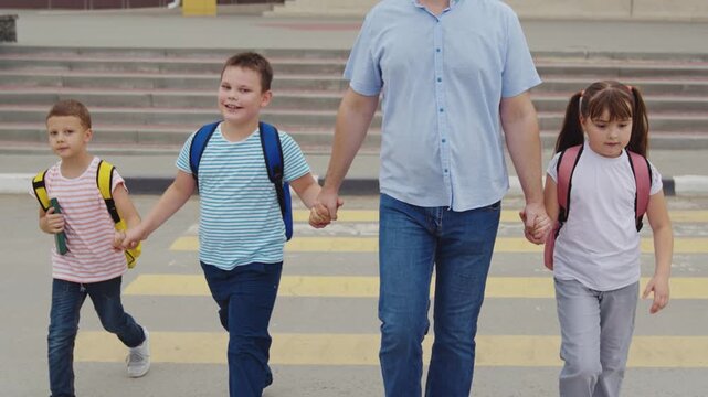 School crossing environment, Paternal protection, Ready for a new school day, Kids in colorful bags, Siblings walk side by side, Urban parent routine, School entrance in morning, Careful pedestrian