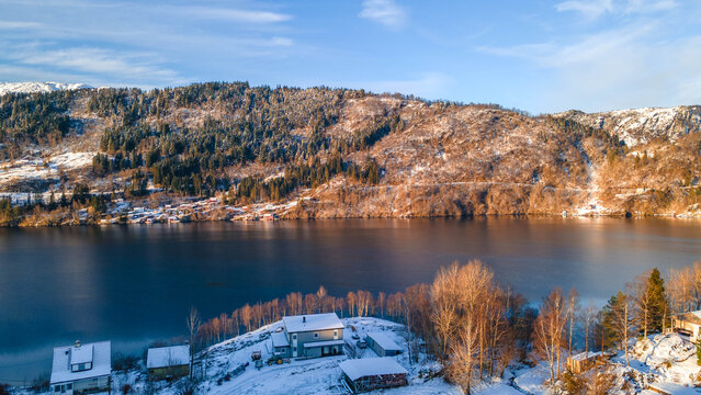 Aerial view of snow-laden mountains embrace the tranquil, dark waters reflecting the winter's stark beauty Norway. Sun and landscape from beautiful place in Norwegian. Aerial View. Winter place. Fiord