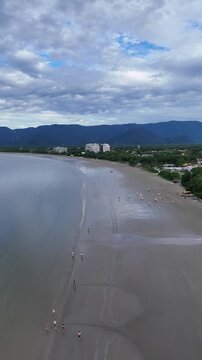Vis&atilde;o a&eacute;rea da Praia do Indai&aacute;, em Bertioga, retratando o cen&aacute;rio litor&acirc;neo com &aacute;guas tranquilas, areia extensa e &aacute;rea urbana ao fundo.