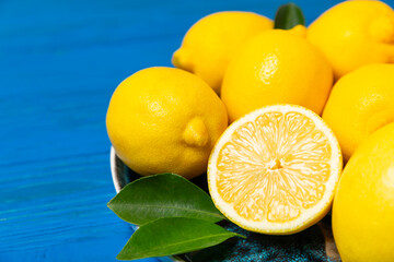 Lemon on a wooden table. Fresh lemon with a slice. Fresh lemon with citrus leaves. Lemon juice. Food and drink ingredients preparing. Healthy eating. Vitamin C. Space for text.