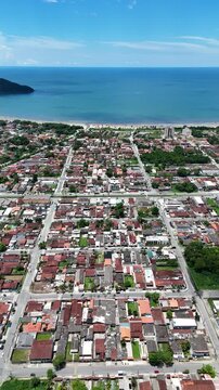 Vis&atilde;o a&eacute;rea da Praia do Indai&aacute;, em Bertioga, mostrando o cen&aacute;rio litor&acirc;neo com &aacute;guas tranquilas, areia clara e a cidade ao fundo.