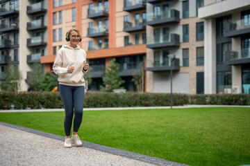 Fototapeta premium Mature woman jogging with headphones in urban park