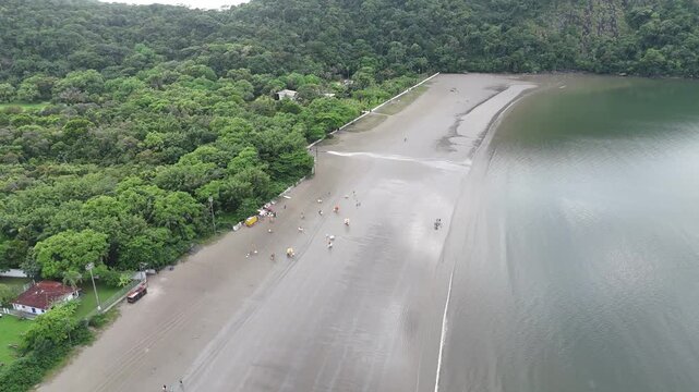 Vis&atilde;o a&eacute;rea da orla da Praia do Indai&aacute; em Bertioga S&atilde;o Paulo mostrando mar, areia e ocupa&ccedil;&atilde;o urbana ao longo do litoral.