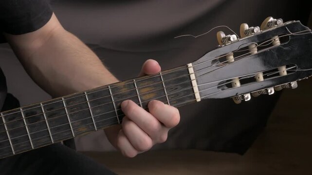 Close-up of male guitarist's hand playing acoustic guitar chords in a cozy indoor setting. close up professional guitar acoustic