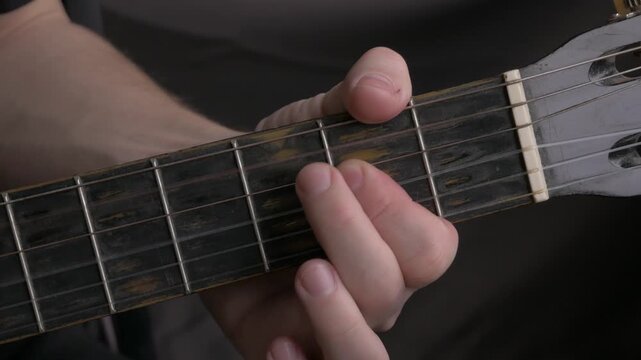 Close-up of hand pressing guitar strings on acoustic guitar, showcasing finger positioning and technique in progression. close up professional guitar acoustic