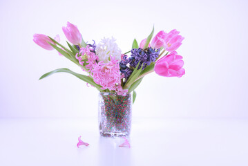 Elegancki wiosenny bukiet kwiatów w szklanym wazonie na jasnym, minimalistycznym tle © Elżbieta Kaps