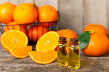 Tangerine essential oil on a wooden table. Bottles of citrus essential oil and sliced ​​fruits. Fragrant tangerine oil with tangerines. Cosmetic oil for spa treatments. Aromatherapy concept. Natural 