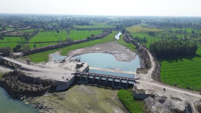 Aerial drone view of a water barrage and bridge in rural farmland