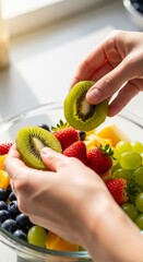 Hands holding kiwi fruit over bowl.