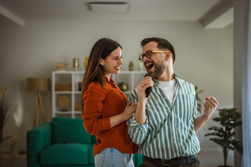 Happy couple enjoying home karaoke singing together