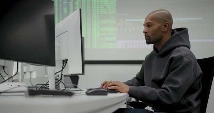 Focused man coding at a modern tech workspace office setup with Computer Monitor