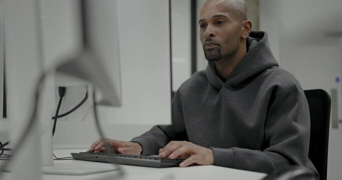 Focused man coding at a modern tech workspace office setup with Computer Monitor